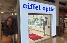 Světelná vstupní brána do obchodu eiffel optic, bílý rám, modrá svítící plexi písmena