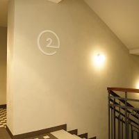 Bílá 3D číslice 2 v kružnici na stěně jako označení druhého patra