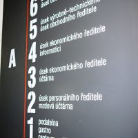 Černá informační deska budovy A, bílé značení pater 1–6 s popisem úseků