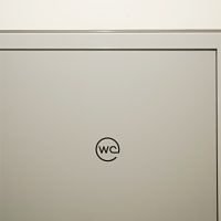 Černé značení WC na horní části šedých dveří