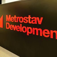 Červené 3D logo Metrostav Development lepené na čele černého recepčního pultu