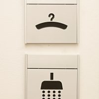 Tabulky s označením místností, gravírovaný černý piktogram ramínka a sprchy, číslo místnosti na hliníkové liště