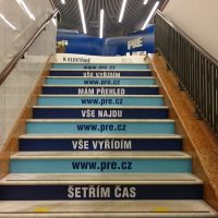 Schody potištěné modrými foliemi s bílými reklamními nápisy, zábradlí, led světla