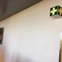 Informační box ve tvaru kostky připevněné na stěně, zeleno-bílé označení piktogram lékarničky, fotoluminiscenční folie