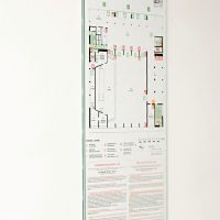 Bílá informační tabule s požárním evakuačním plánem ČZU, připevněno na bílé zdi chodby