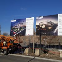 Instalace dvou reklamních billboardů před rozestavěný areál, vůz s vysokozdvižnou plošinou