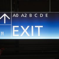 Světelná navigační stropní výstrč, modrý box, bílý nápis EXIT, označení sektorů, šipka nahoru a piktogram příbor