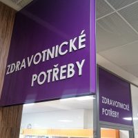 Fialová reklamní výstrč s bílým 3D nápisem Zdravotnické potřeby, výloha obchodu s polepem