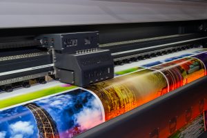 Hlava tiskového stroje v průběhu tisku barevných plakátů na lesklý papír