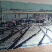 Wallwrap fototapeta potištěná fotografií vlakového nádraží a kolejí, nalepená na zdi, béžová podlaha