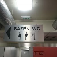 Závěsná stříbrná tabule s černým označením BAZÉN, WC, přišroubovaná na stropě, ventilační potrubí