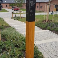 Navigační totem v areálu Czech Equestrian Team, gravírovaný černý matný dibond na lakovaném trámu, dlážděné schody a cesty